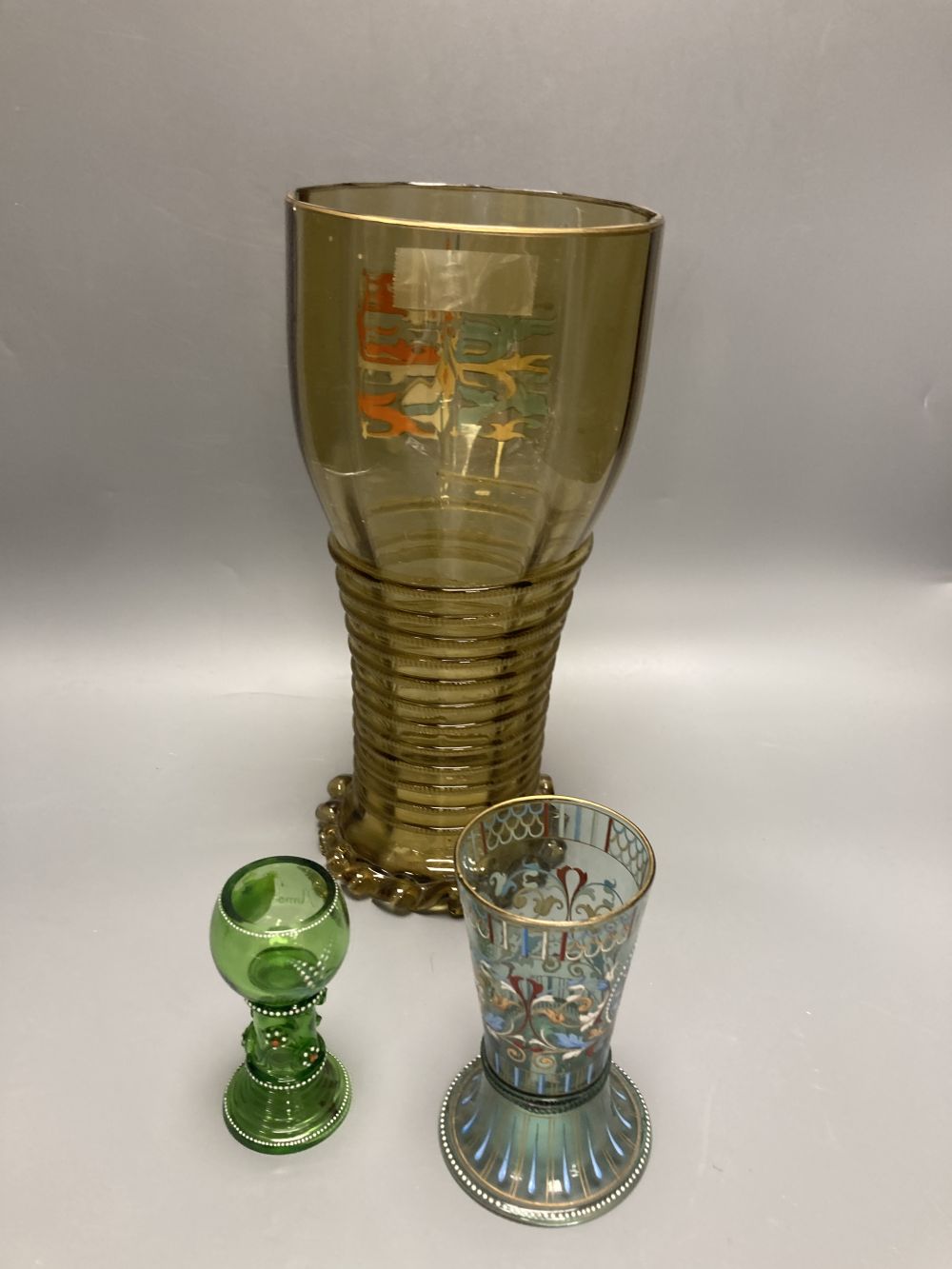 A large German historismus enamelled glass humpen, 30cm and two similar glasses